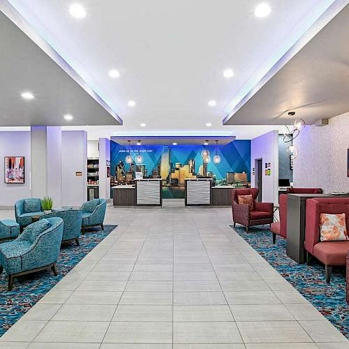 The image depicts a modern hotel lobby with a reception desk, colorful seating areas, and wall art, all under bright ceiling lights.