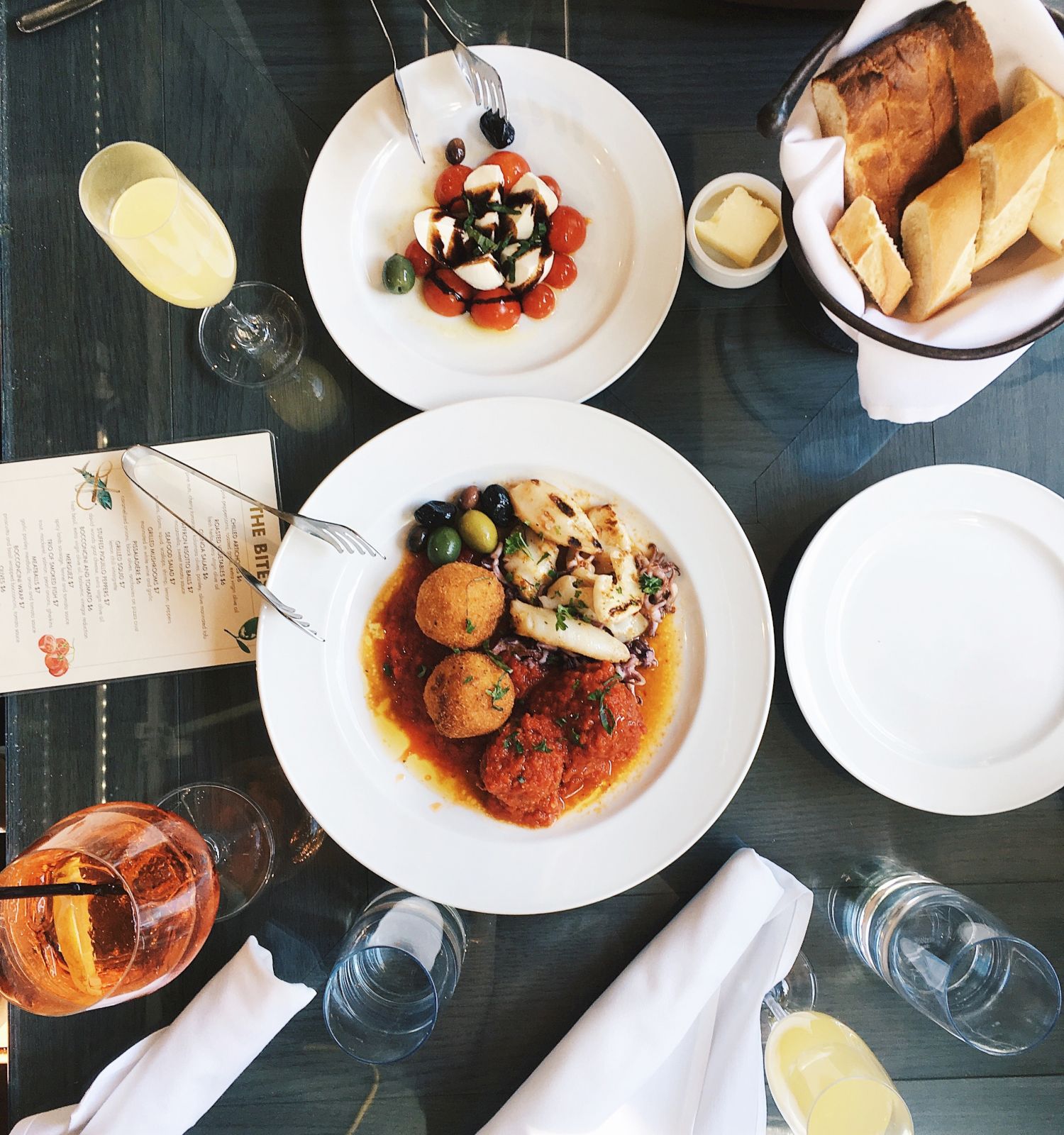 The image shows a table set with various dishes including a main course, salad, bread, and drinks. There are also plates, utensils, and napkins.